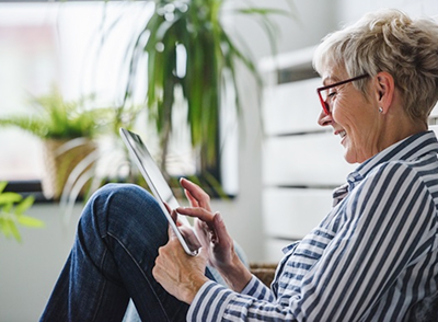 Smiling beautiful senior woman using digital tablet at home