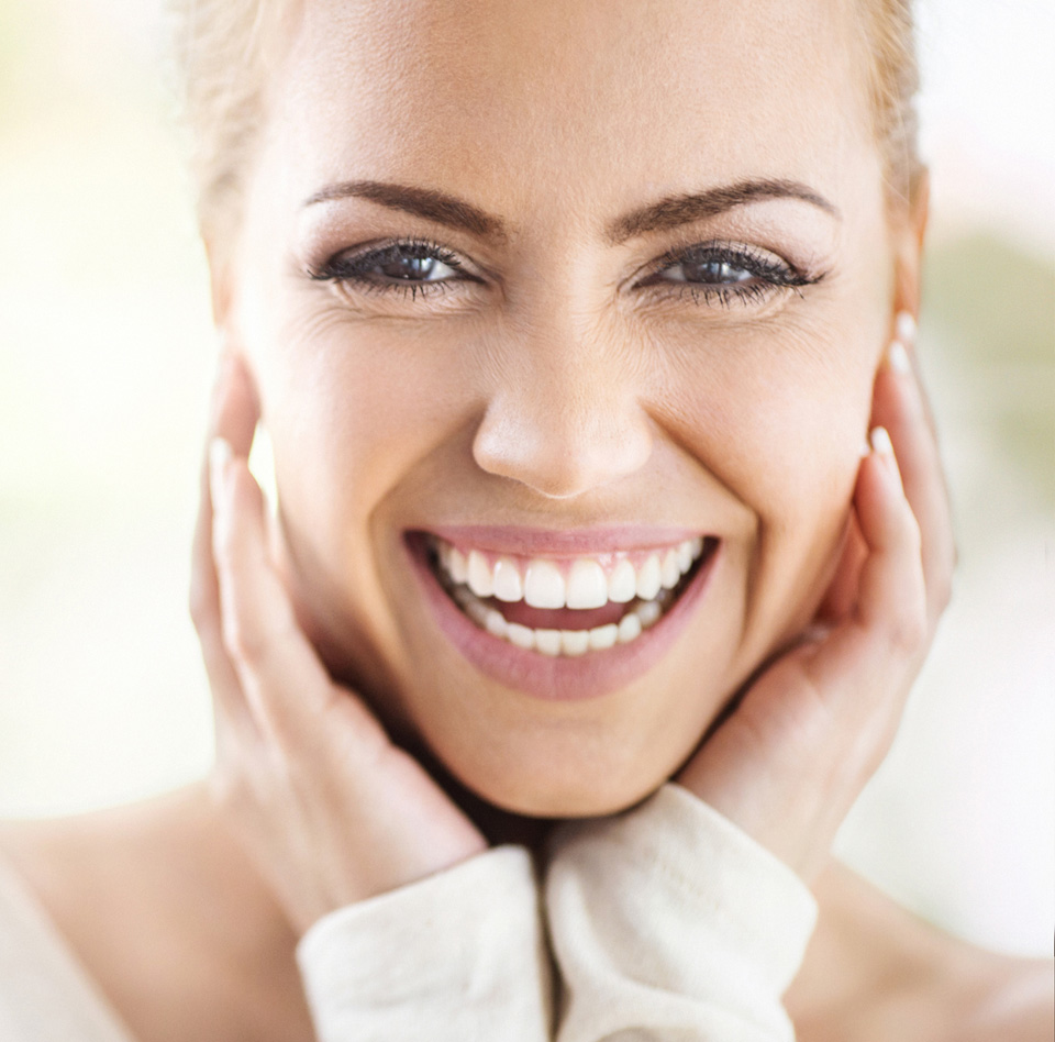 Closeup portrait of an attractive mid 30's woman gently touching her neck and smiling