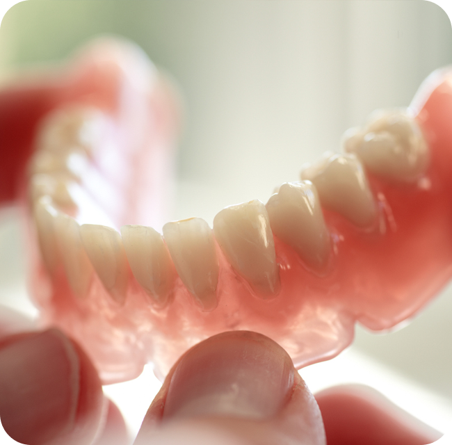 Dental technician holding a denture.