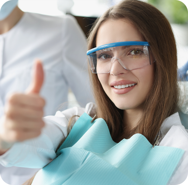 Portrait of smiling woman holding her thumbs up at dentist appointment