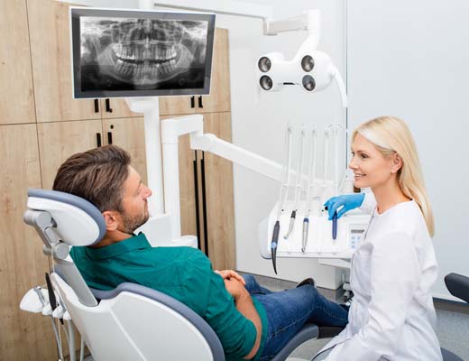 Beautiful woman dentist consulting a man patient in the dental office. Stomatology and health care concept