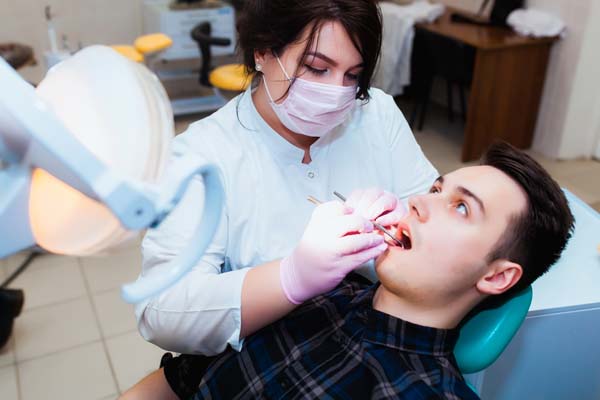Young professional doctor dentist in a modern office with dental equipment. The concept of health insurance and free dental care. Prosthetics and installation of veneers.