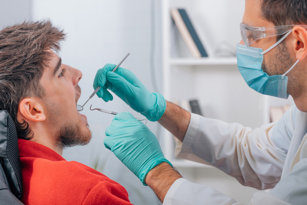dentist with tools working in the patient's mouth